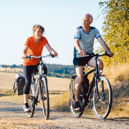An active senior couple riding bicycles on a path together